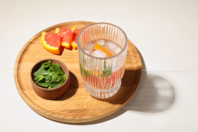 Photo of Delicious refreshing drink with sicilian orange and mint near fresh ingredients on white wooden table