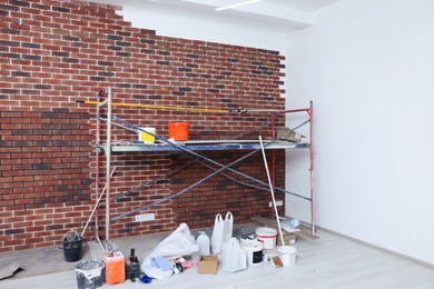 Scaffolding and equipment near brick wall with tile leveling system in repaired room