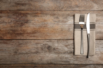 Photo of Cutlery and napkin on wooden background, top view. Table setting