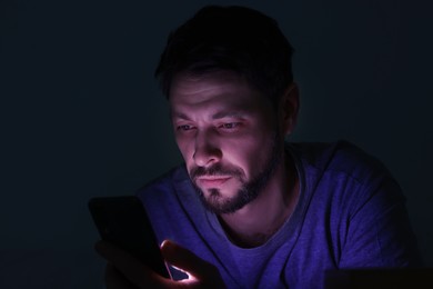 Photo of Man using smartphone at night. Internet addiction