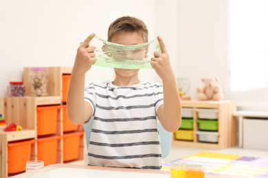 Photo of Little boy playing with slime in room