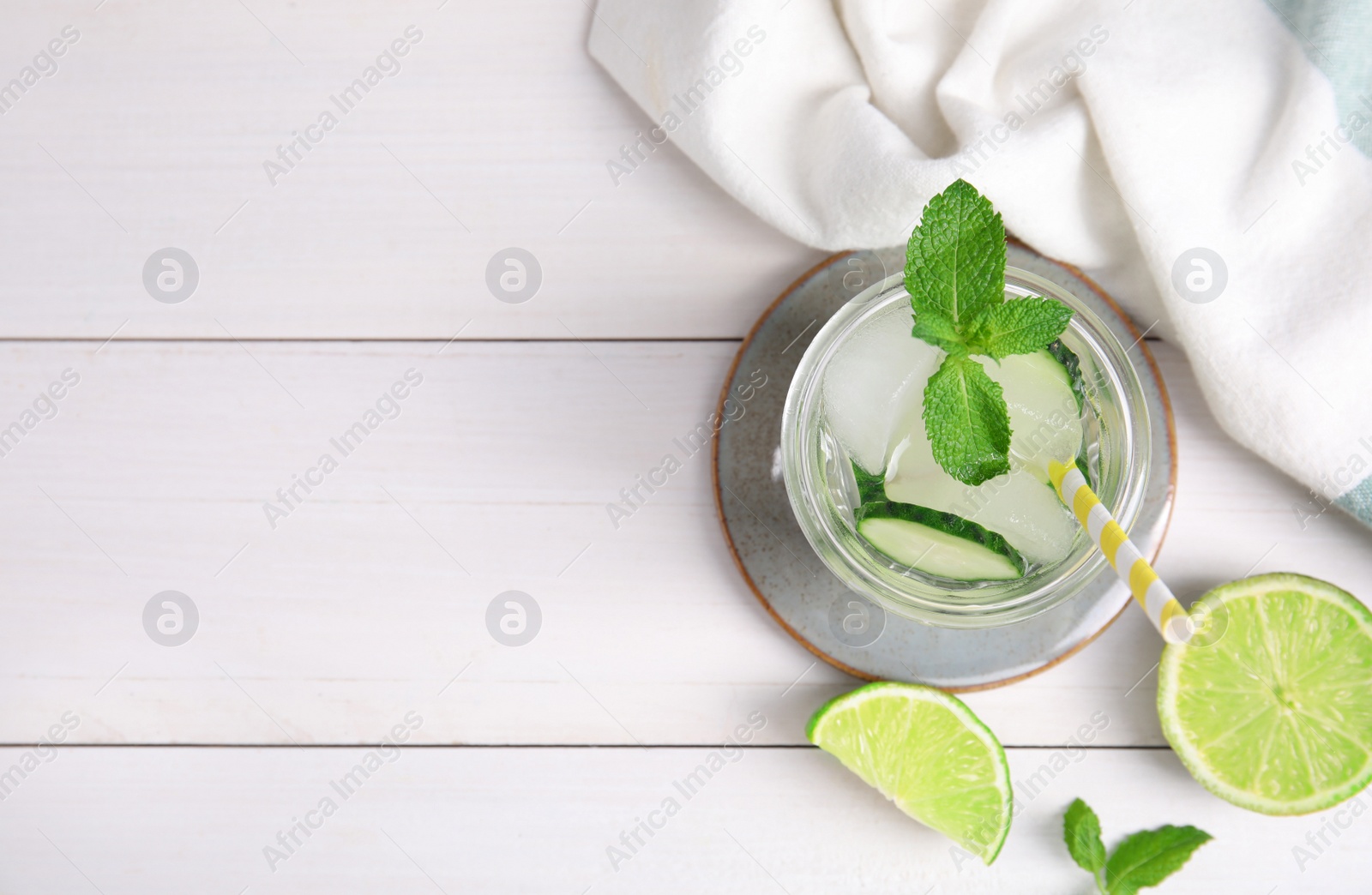 Photo of Glass of refreshing cucumber water with mint on white wooden table, flat lay. Space for text