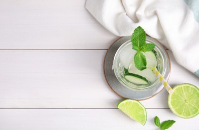 Glass of refreshing cucumber water with mint on white wooden table, flat lay. Space for text