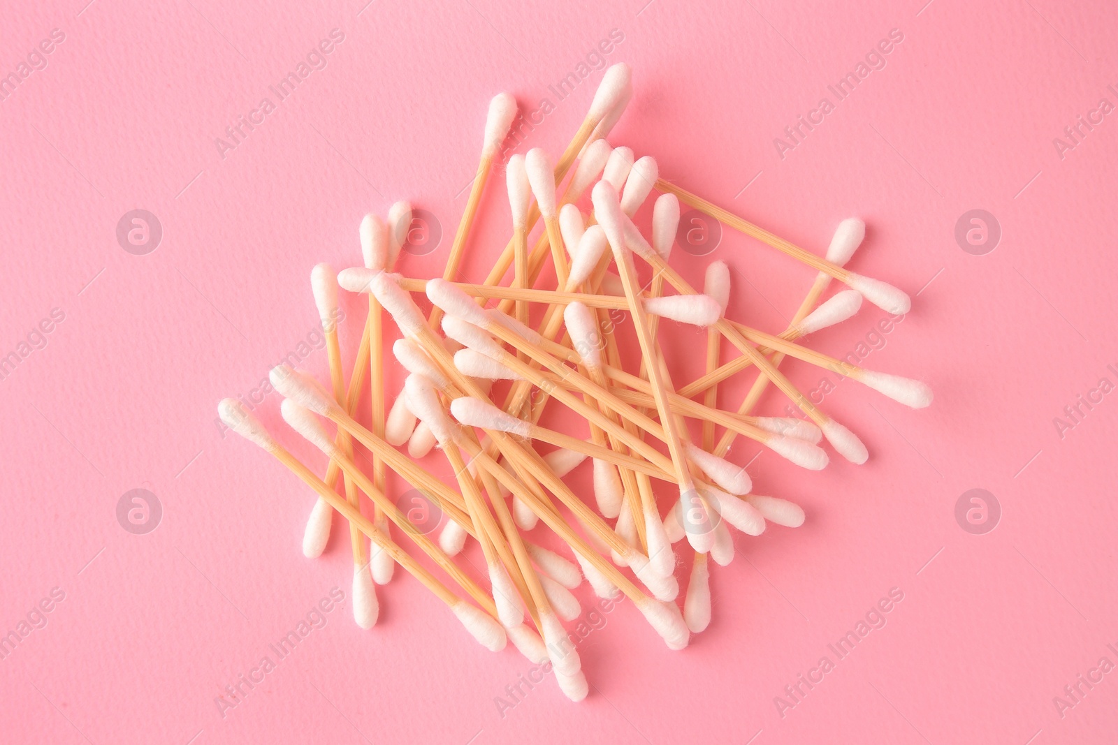 Photo of Heap of clean cotton buds on pink background, flat lay