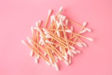 Heap of clean cotton buds on pink background, flat lay