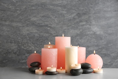 Photo of Beautiful composition with candles and stones on table against grey background. Space for text