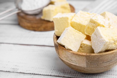 Photo of Bowl with tasty marshmallows on white wooden table, closeup. Space for text