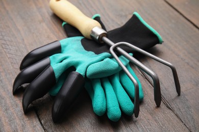 Photo of Claw gardening gloves and rake on wooden table
