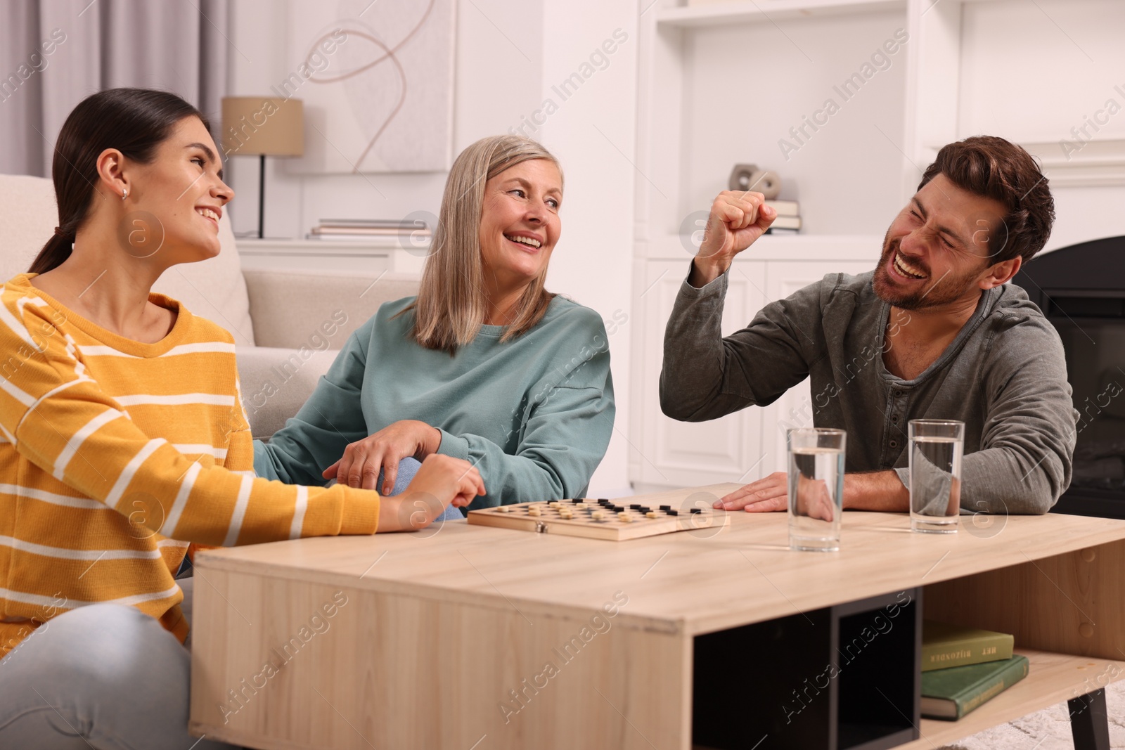 Photo of Family talking while playing checkers at home