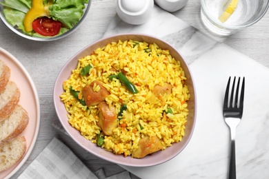 Photo of Delicious rice pilaf with meat served on table, flat lay