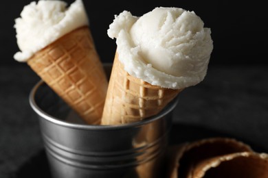 Photo of Ice cream scoops in wafer cones on gray table, closeup