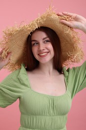 Portrait of beautiful woman with freckles in straw hat on pink background