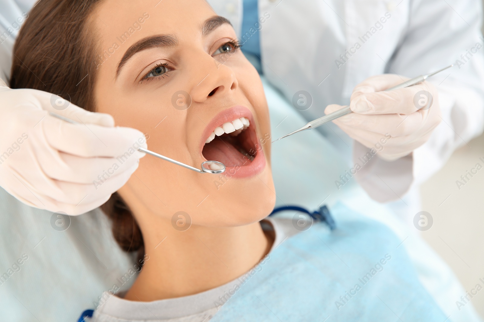 Photo of Dentist examining patient's teeth in modern clinic