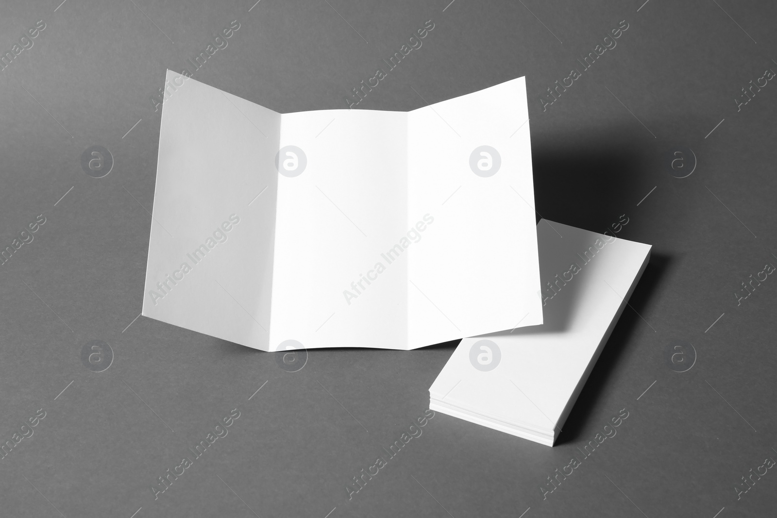 Photo of Empty flyers on grey background. Mockup for design