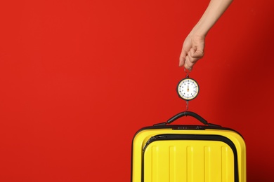 Photo of Woman weighing suitcase against color background, closeup. Space for text