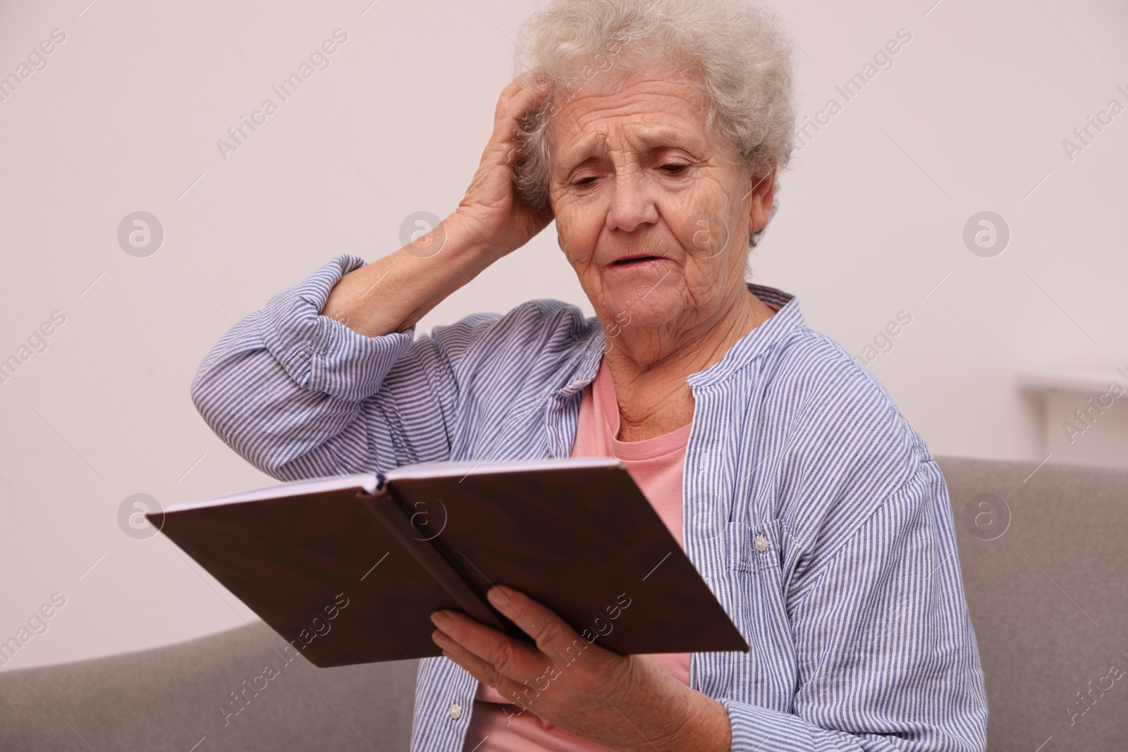 Photo of Senior woman with notebook at home. Age-related memory impairment