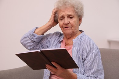 Photo of Senior woman with notebook at home. Age-related memory impairment