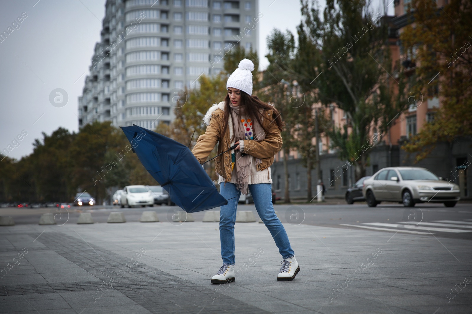 Photo of Woman with blue umbrella caught in gust of wind on street