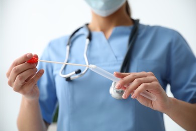 Photo of Doctor holding buccal cotton swab and tube for DNA test in clinic, closeup
