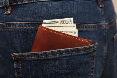 Photo of Wallet with dollar banknotes in pocket of jeans, closeup. Spending money