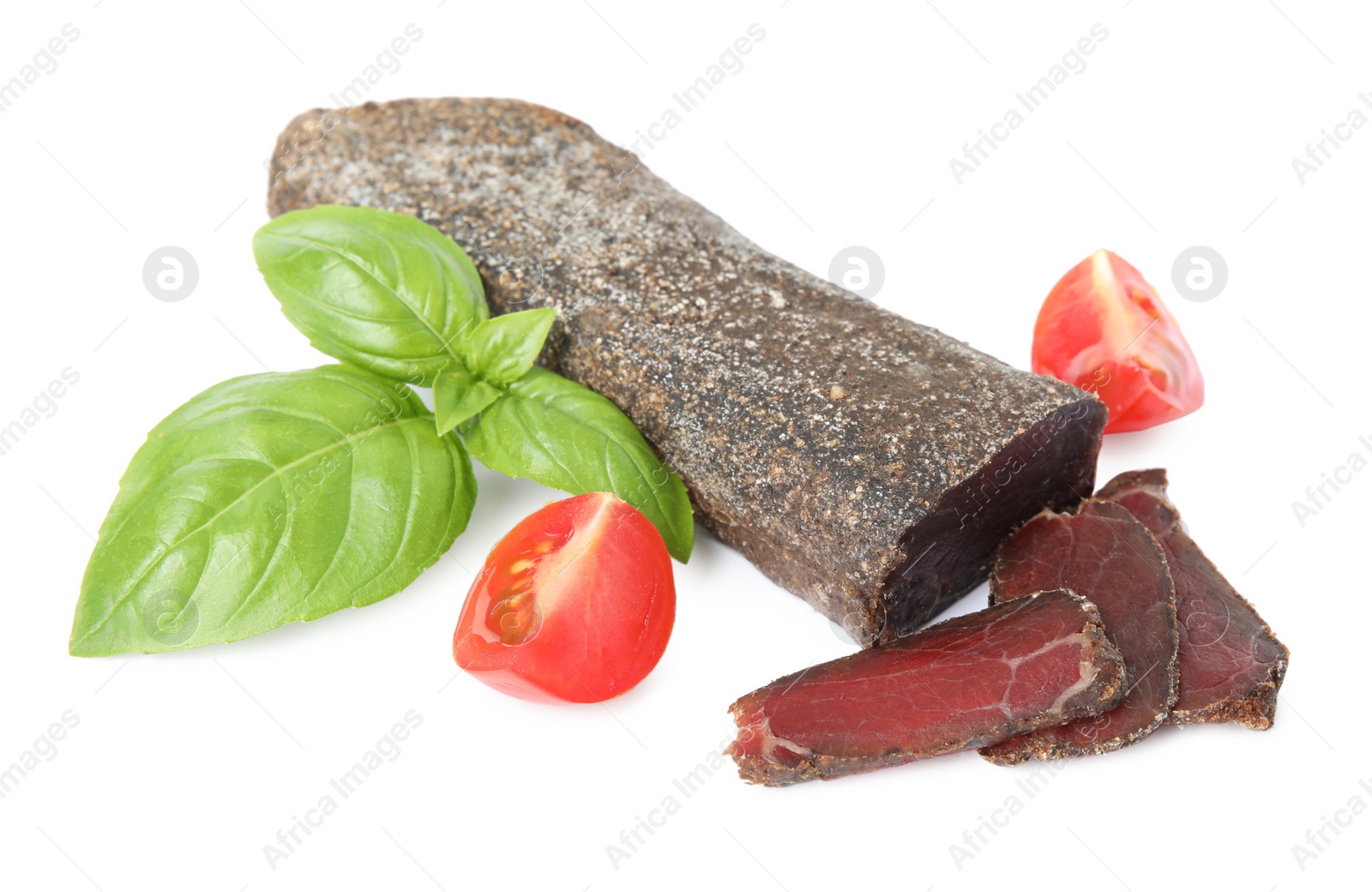 Photo of Delicious dry-cured beef basturma with basil and tomato on white background