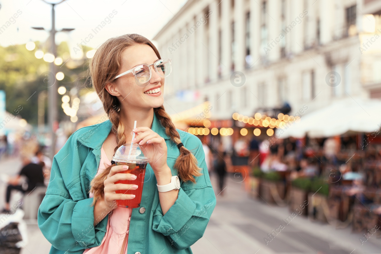 Photo of Young woman with refreshing drink on city street. Space for text