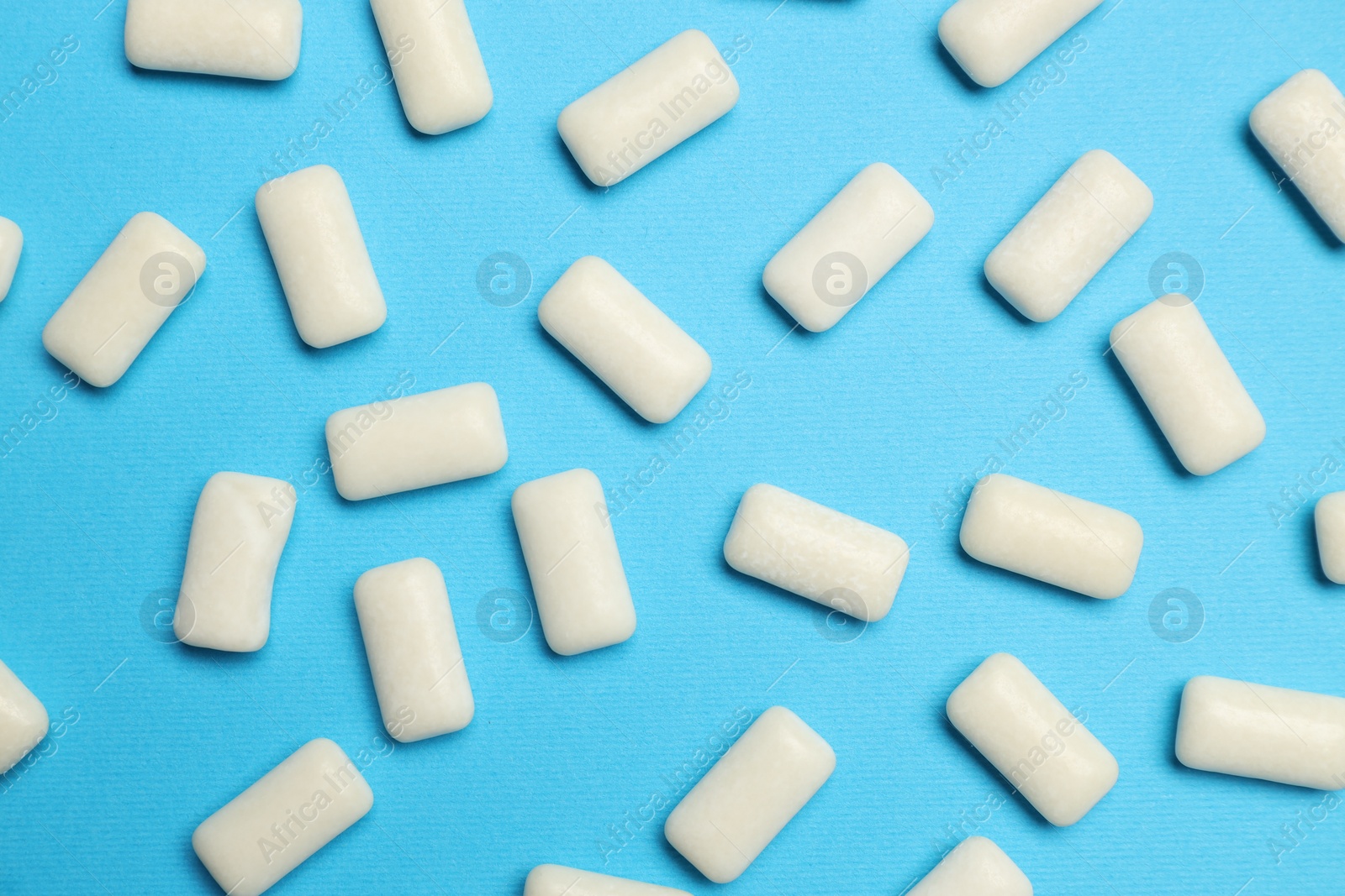 Photo of White bubble gums on blue background, flat lay