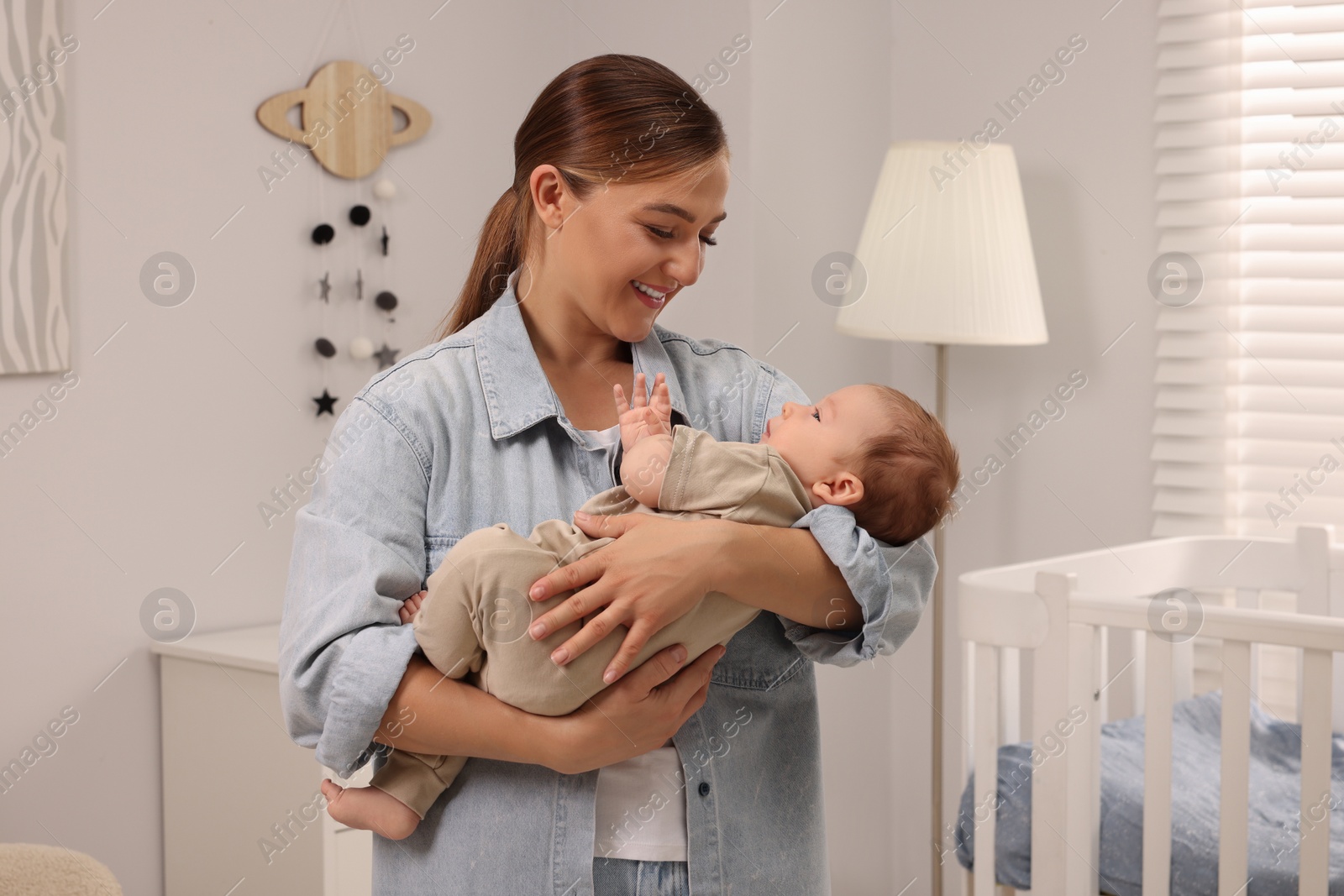 Photo of Mother holding her cute newborn baby in child's room