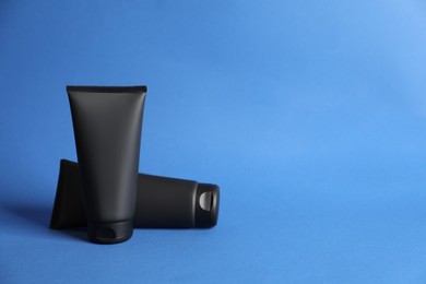 Photo of Tubes of men's facial creams on blue background. Mockup for design