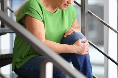 Senior woman suffering from knee pain indoors, closeup