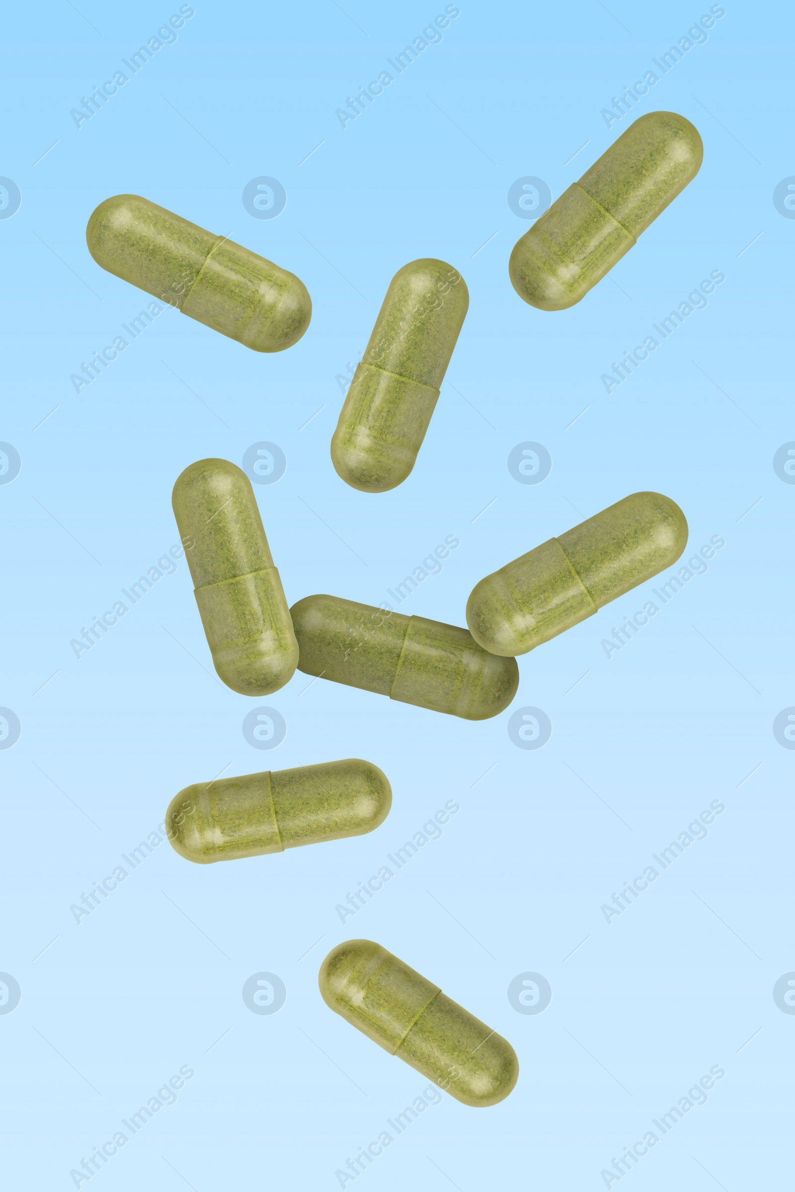 Image of Vitamin. Capsules falling on light blue gradient background