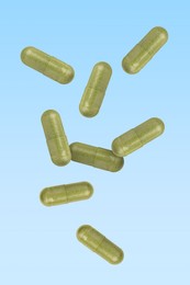 Image of Vitamin. Capsules falling on light blue gradient background