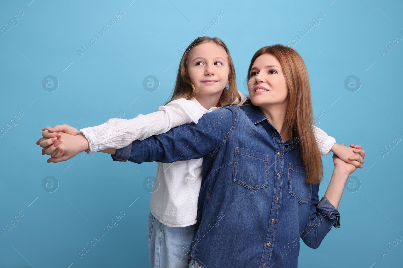 Photo of Portrait of happy mother and her cute daughter on light blue background