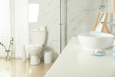 Photo of Toilet bowl near shower stall in modern bathroom interior