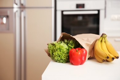 Photo of Fresh food in paper bag on table in kitchen