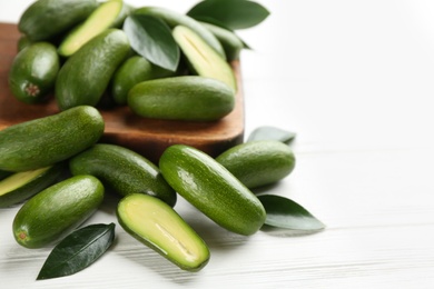 Photo of Fresh seedless avocados with green leaves on white wooden table, closeup. Space for text