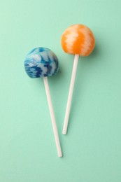 Tasty lollipops on turquoise background, flat lay