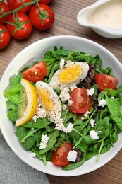 Photo of Delicious salad with boiled egg, tomatoes and cheese served on wooden table, flat lay