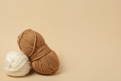 Photo of Soft woolen yarns on beige background, space for text