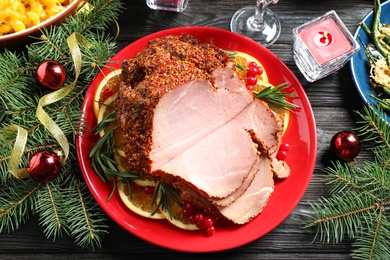 Plate with delicious ham served on dark wooden table, flat lay. Christmas dinner
