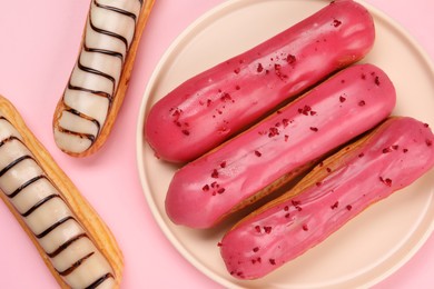 Photo of Delicious eclairs covered with glaze on pink background, flat lay