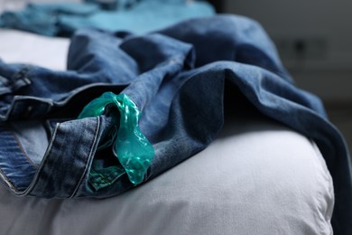 Photo of Unrolled condom and jeans on bed. Safe sex