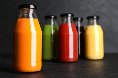 Photo of Bottles with delicious colorful juices on black table
