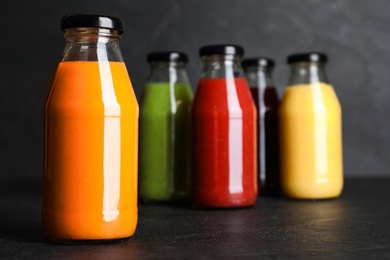 Bottles with delicious colorful juices on black table