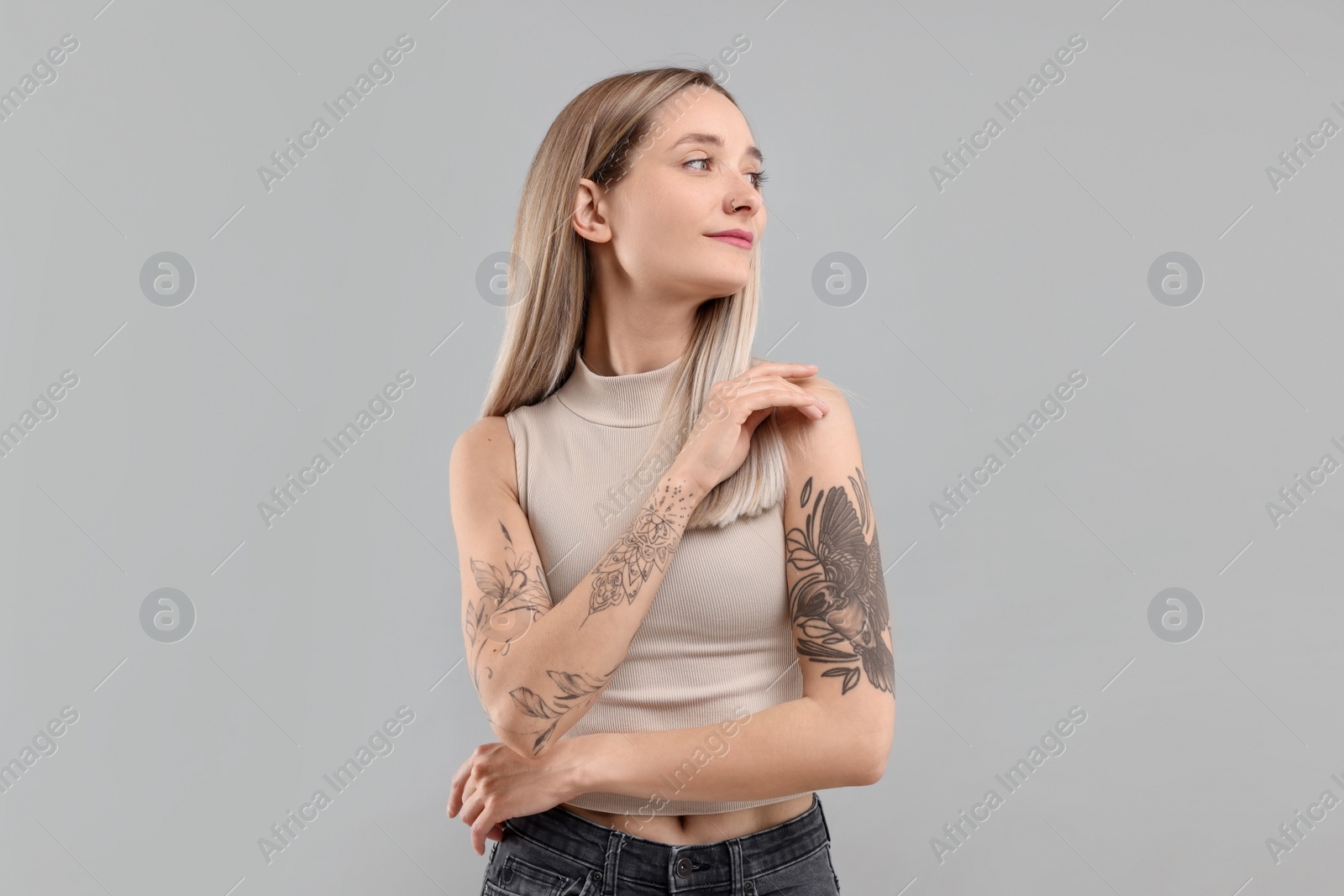 Photo of Portrait of beautiful tattooed woman on gray background