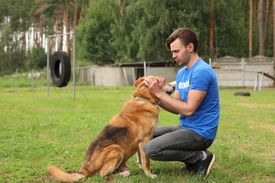 Photo of Male volunteer with homeless dog at animal shelter outdoors