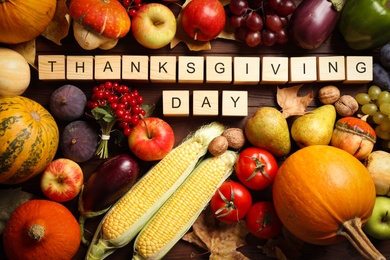 Cubes with phrase THANKSGIVING DAY, autumn fruits and vegetables on wooden background, flat lay. Happy holiday