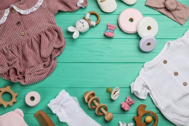 Frame of baby clothes and accessories on green wooden table. Space for text