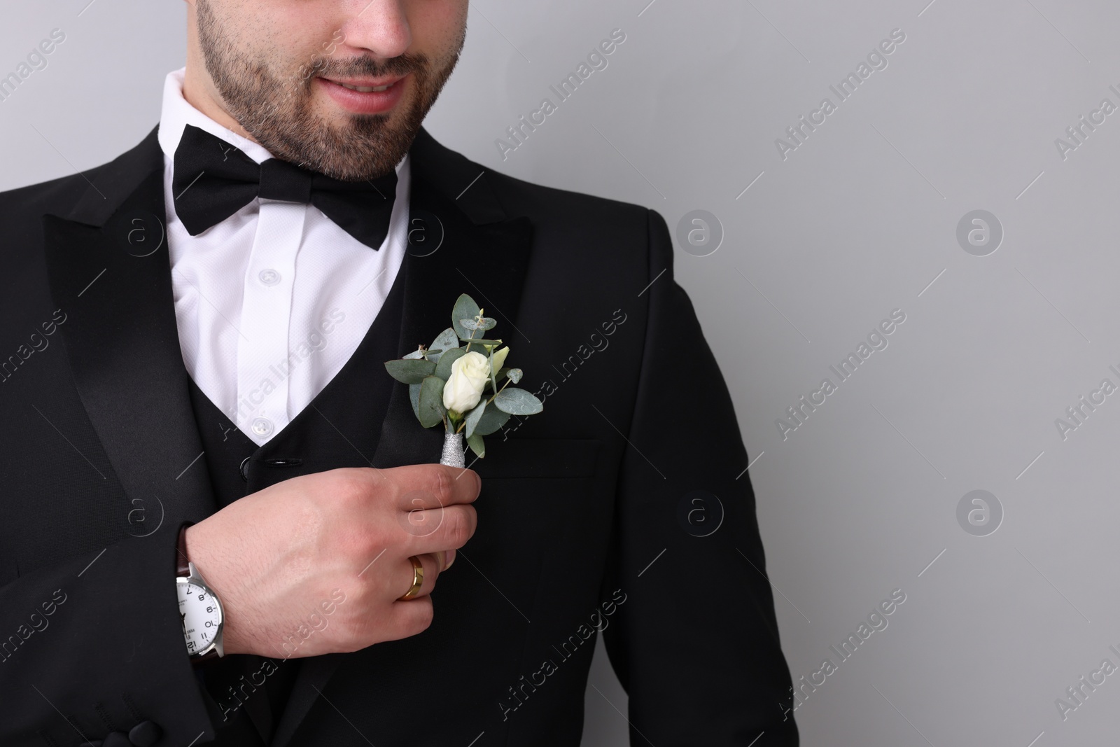 Photo of Groom with boutonniere on light grey background, closeup. Wedding accessory