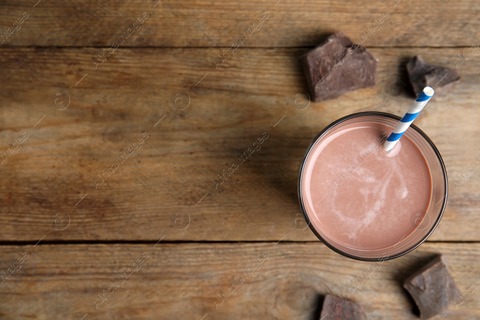 Photo of Delicious chocolate milk on wooden table, flat lay. Space for text